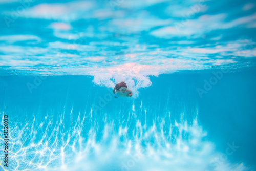 Child splashing in swimming pool. Child boy swim under water in sea. Kid swimming in pool underwater. Happy boy swims in sea underwater, active kid swimming, playing and diving.