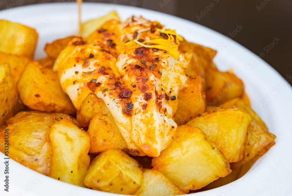 Traditional patatas bravas with aioli sauce, Spanish food, selective approach to the sauce.