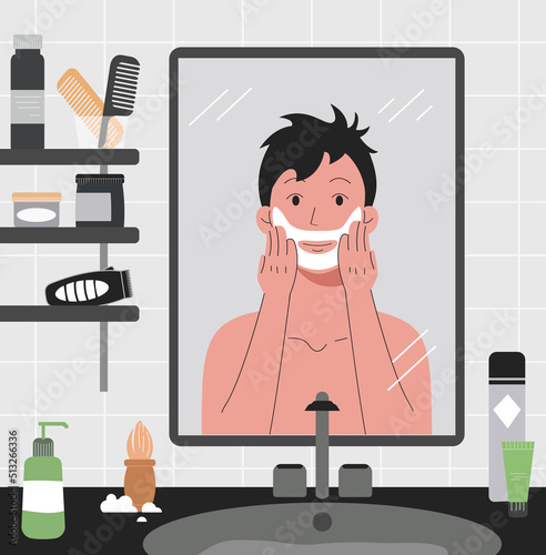 A man shaves in front of the bathroom mirror