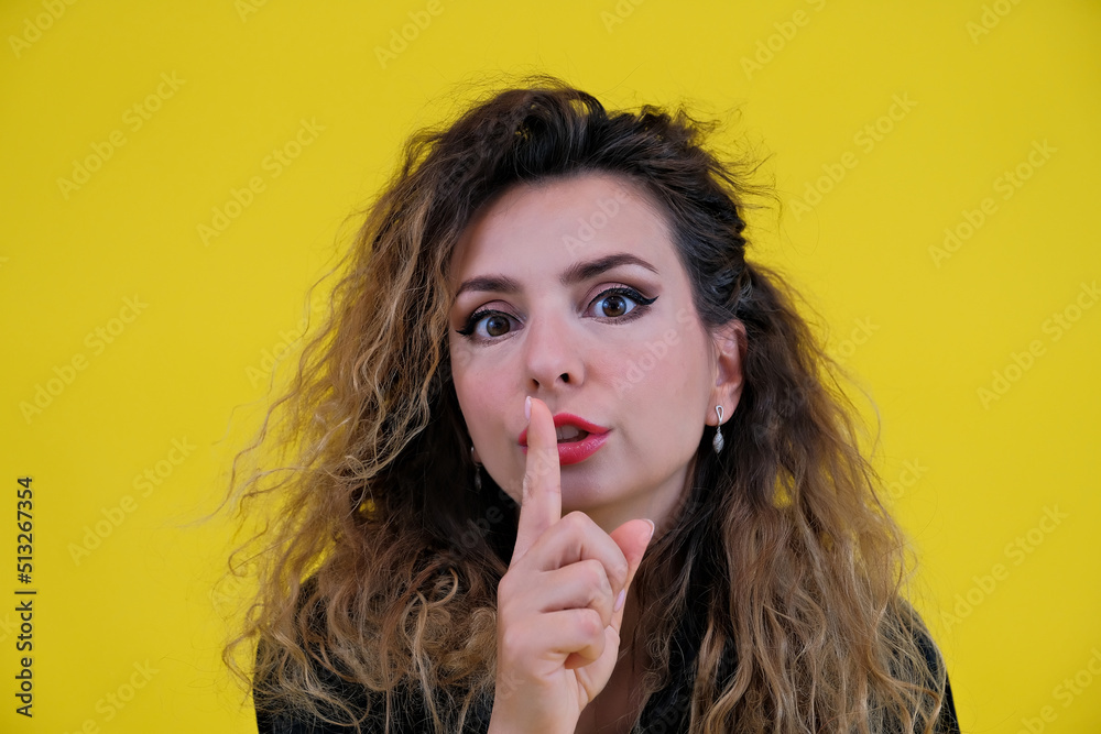 Close-up portrait beautiful girl on a yellow background. woman showing finger silence, girl showing shh sign keep secret Close-up portrait beautiful girl on a yellow background. woman showing finger silence, girl showing shh sign keep secret