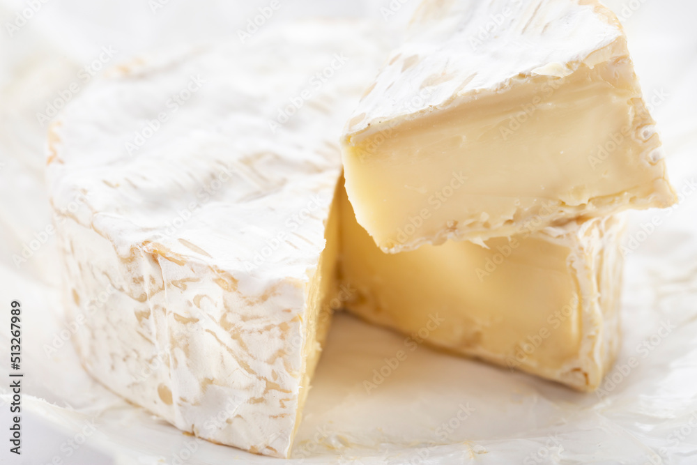 Brie type of cheese. Close up on Camember cheese. Pieces of soft cheese reveal its runny cream texture.