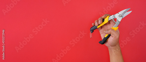 hand holding tin snips aviation snips isolated red background