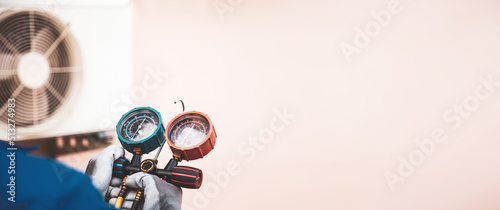 Mechanic air conditioner technician using manifold gauge checking refrigerant for filling home air conditioning and air duct cleaning and maintenance outdoor compressor unit.