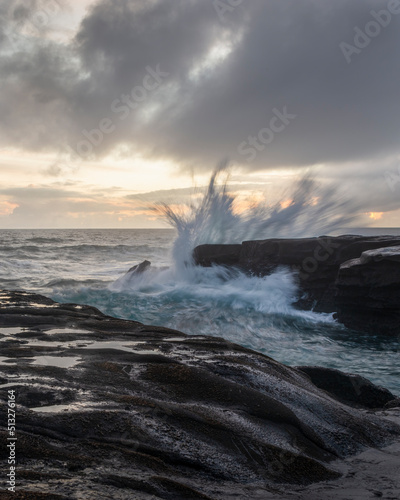 Ocean waves crashing on rocks at Muriwai beach, Auckland. Vertical format.