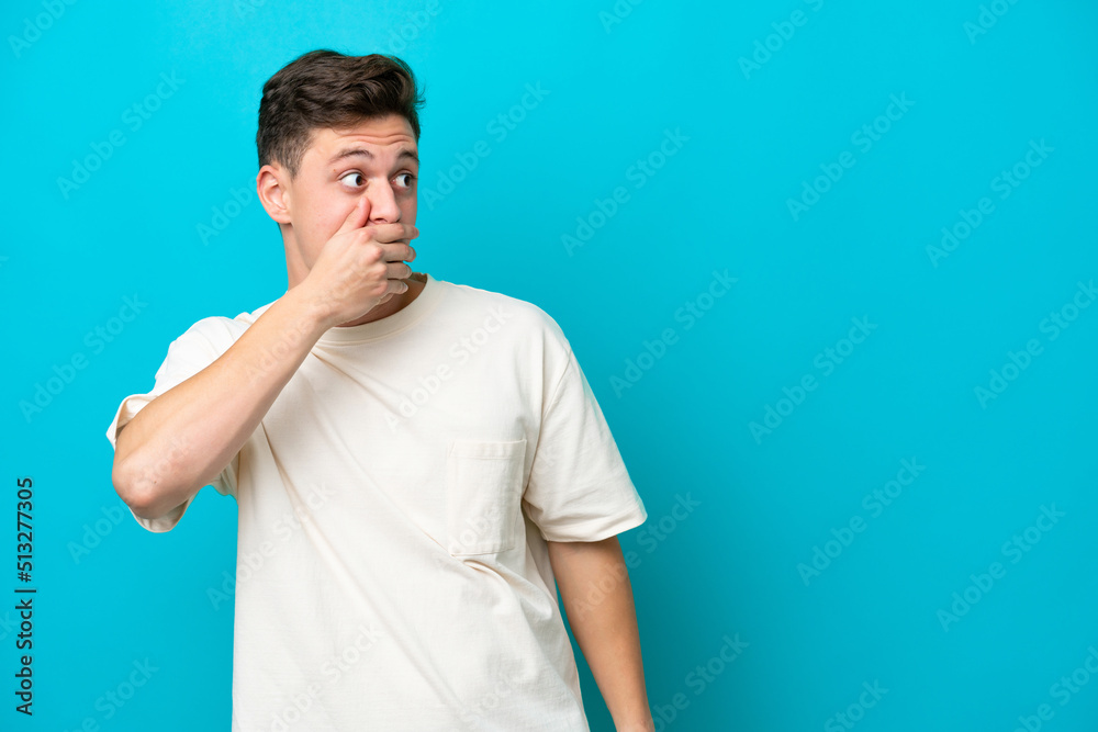 Young handsome Brazilian man isolated on blue background doing surprise gesture while looking to the side Young handsome Brazilian man isolated on blue background doing surprise gesture while looking to the side