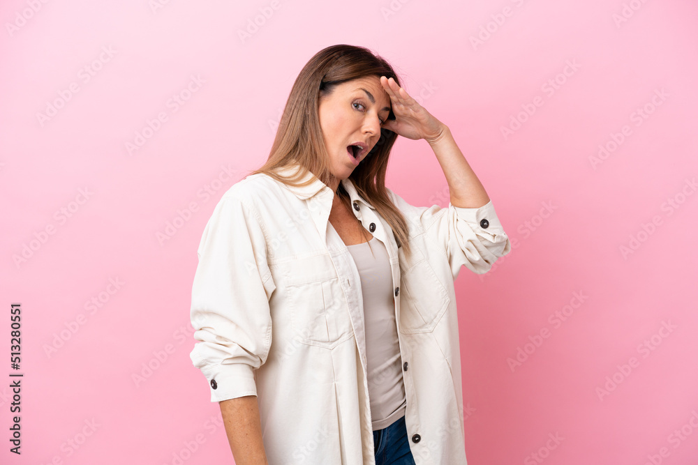 Middle age caucasian woman isolated on pink background doing surprise gesture while looking to the side Middle age caucasian woman isolated on pink background doing surprise gesture while looking to the side