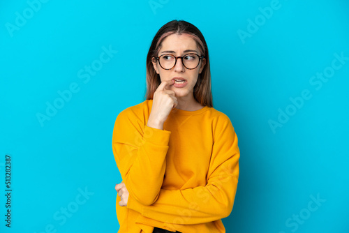 Young caucasian woman isolated on blue background nervous and scared photo