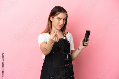 Young hairdresser woman isolated on pink background making money gesture