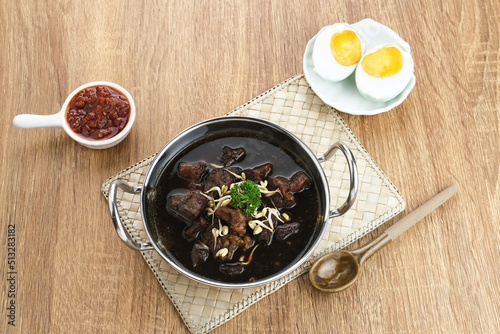 Rawon, Indonesian Traditional beef black soup. Served on a bowl with mung bean sprouts, chilli paste and salted egg
 photo