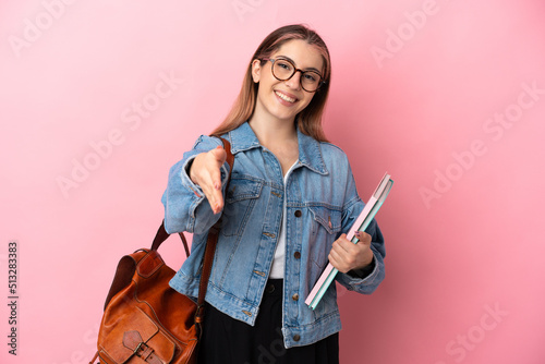 Fotografie Young caucasian student woman isolated on pink background shaking hands for clos