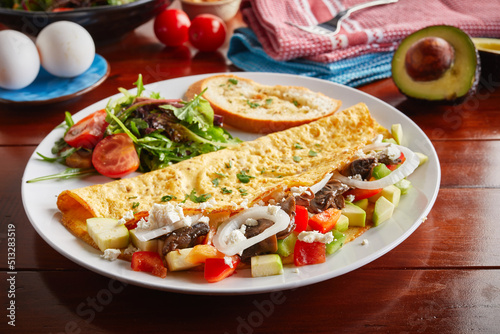 Zucchini omelette roll with salad served in a dish isolated on wooden background side view