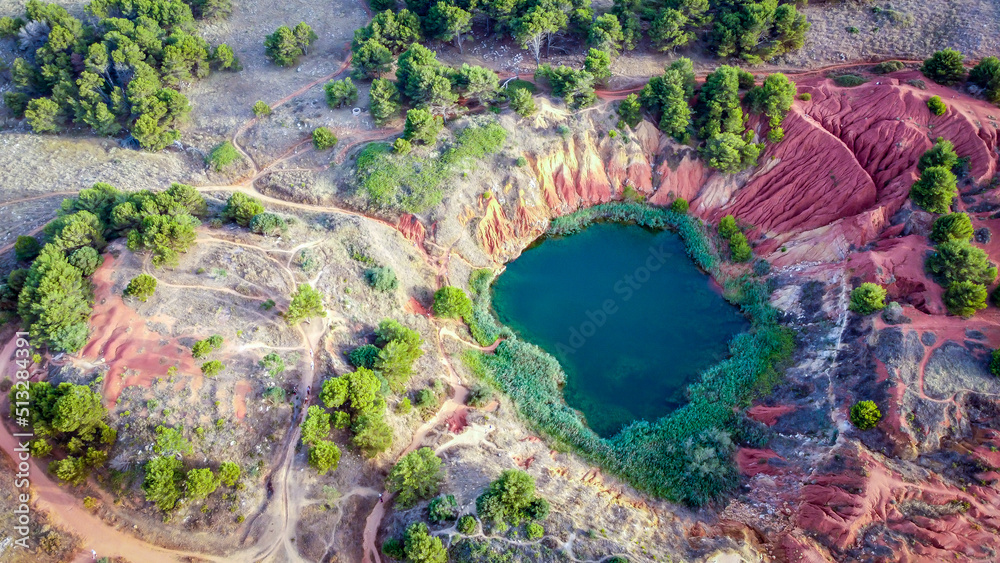 The lake in old bauxite's red soils quarry cave in Apulia, Otranto, Salento, Italy. The digging was filled with natural waters