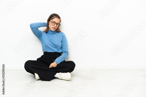 Young Caucasian woman sitting on the floor with neckache