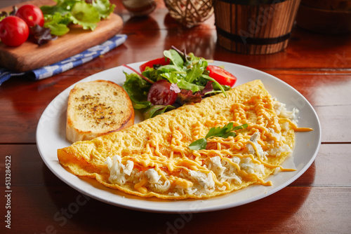 Triple Cheese omelette roll with salad served in a dish isolated on wooden background side view