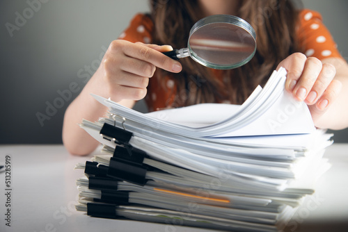 woman using magnifying glass with documents