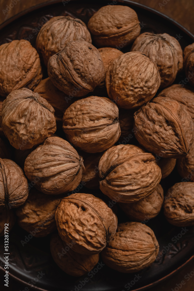 Unpeeled brown walnuts close up on a dark plate. Unpeeled brown walnuts close up on a dark plate.