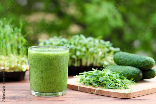 Green vegetable smoothie against background of greenery and microgreen. Healthy, vegan food. Selective focus