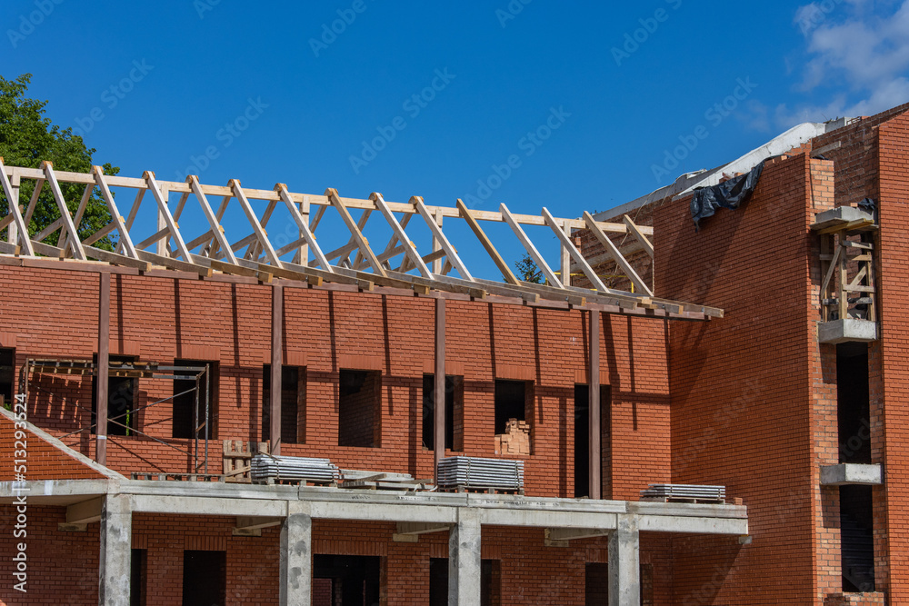 Construction of a large red brick Catholic church. Construction of a peaked roof from wooden beams Construction of a large red brick Catholic church. Construction of a peaked roof from wooden beams