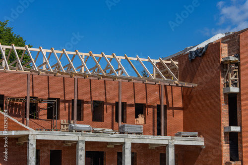 Construction of a large red brick Catholic church. Construction of a peaked roof from wooden beams