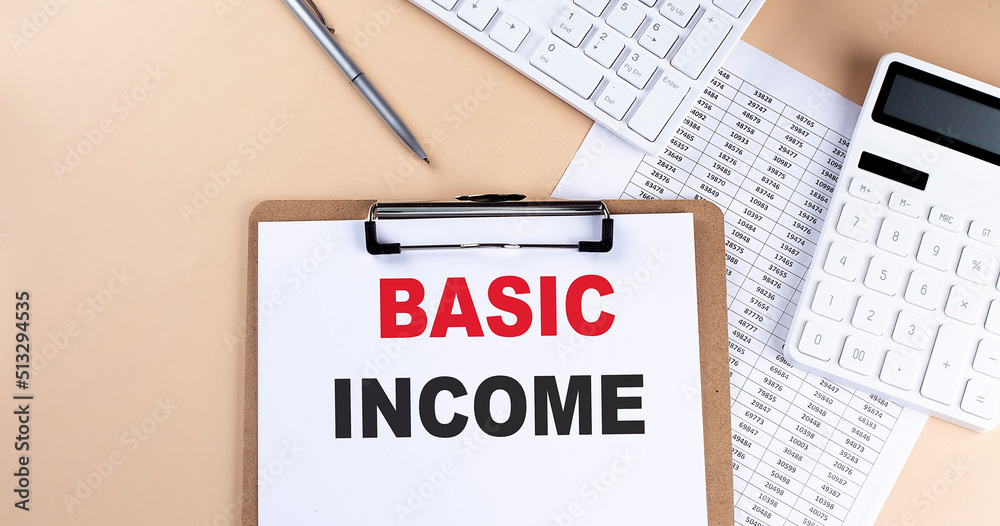 clipboard with white blank paper text BASIC INCOME , keyboard calculator and chart, top view. business concept. clipboard with white blank paper text BASIC INCOME , keyboard calculator and chart, top view. business concept.