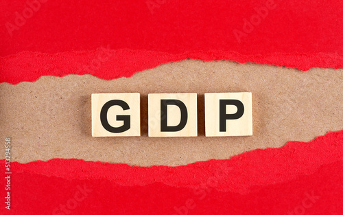 GDP word on wooden cubes on red torn paper , financial concept background