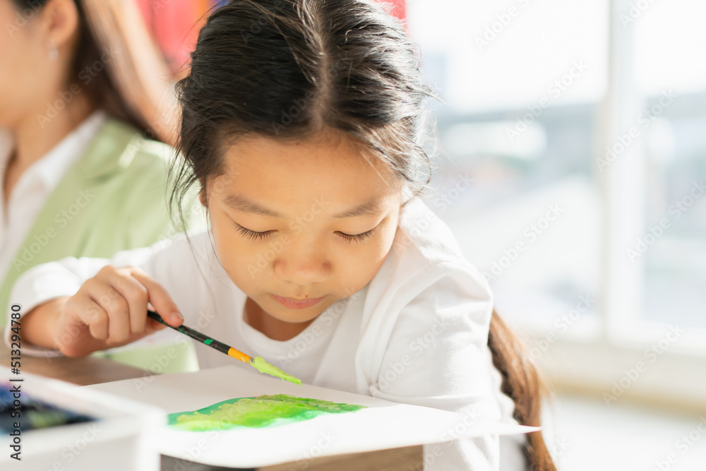 beautiful young children think, wear white shirt, look at paper, hold paintbrush, painting color in education classroom. asian beautiful children happy and fun color painting education in small school beautiful young children think, wear white shirt, look at paper, hold paintbrush, painting color in education classroom. asian beautiful children happy and fun color painting education in small school