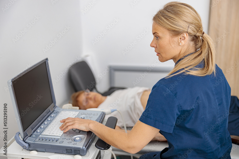 Fototapeta premium Focused doctor ultrasound examine senior patient abdomen at hospital. Prenatal diagnosis center
