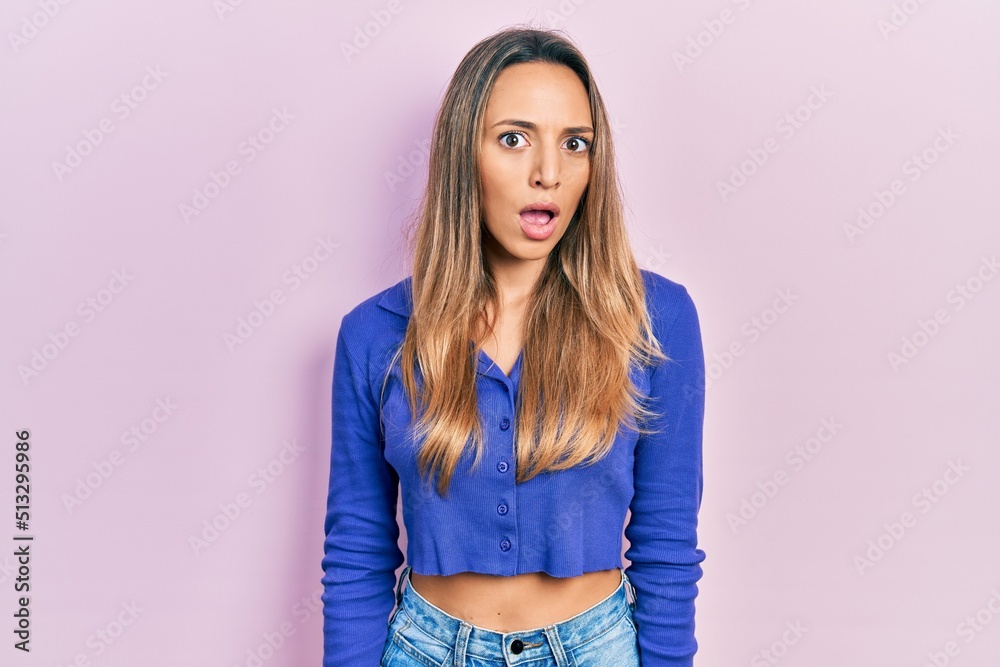 Beautiful hispanic woman wearing casual blue shirt in shock face, looking skeptical and sarcastic, surprised with open mouth Beautiful hispanic woman wearing casual blue shirt in shock face, looking skeptical and sarcastic, surprised with open mouth