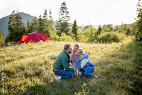 Portrait of a lovely couple with little girl hug together while travel in the mountains. Young caucasian family spend summer time on nature