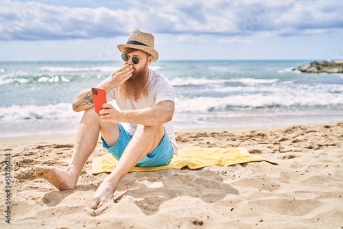Wallpaper Mural Young redhead man making selfie by the smartphone sitting on the towel at the beach. Torontodigital.ca