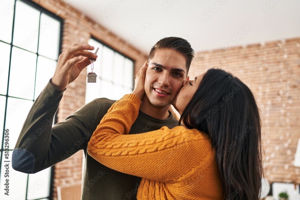 Man and woman couple kissing hugging each other holding key of new house at new home