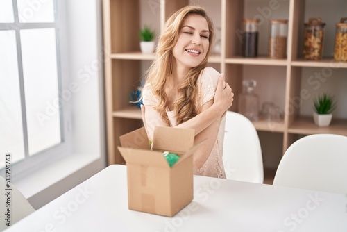 Beautiful blonde woman with cardboard box hugging oneself happy and positive, smiling confident. self love and self care © Krakenimages.com