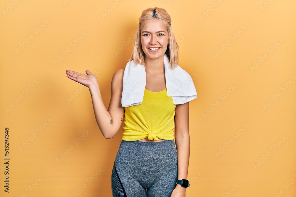 Beautiful blonde sports woman wearing workout outfit smiling cheerful presenting and pointing with palm of hand looking at the camera. Beautiful blonde sports woman wearing workout outfit smiling cheerful presenting and pointing with palm of hand looking at the camera.