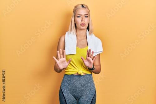 Beautiful blonde sports woman wearing workout outfit moving away hands palms showing refusal and denial with afraid and disgusting expression. stop and forbidden.