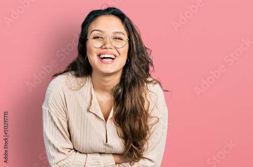 Young hispanic girl wearing casual clothes and glasses smiling and laughing hard out loud because funny crazy joke. © Krakenimages.com