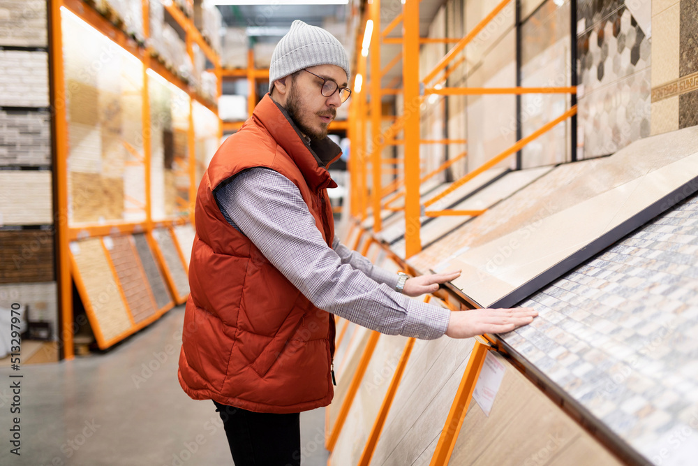 a man in a decorating store chooses flooring and wall tiles a man in a decorating store chooses flooring and wall tiles