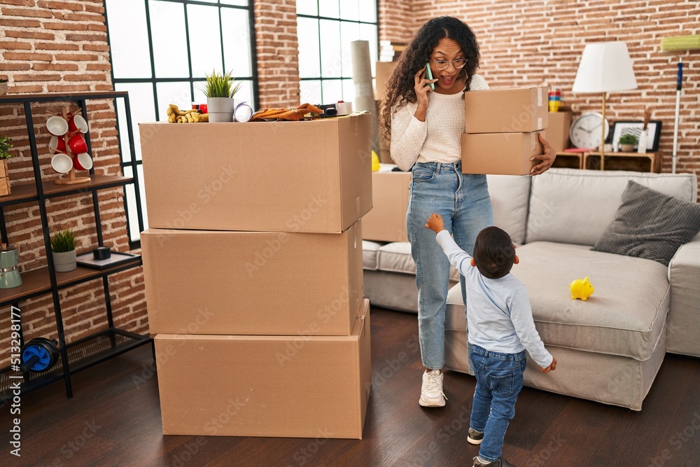 Mother and son talking on the smartphone holding package at new home Mother and son talking on the smartphone holding package at new home