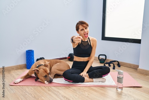 Young beautiful woman sitting on yoga mat pointing displeased and frustrated to the camera, angry and furious with you