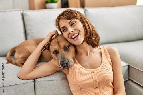Young caucasian woman hugging dog sitting on floor at home
