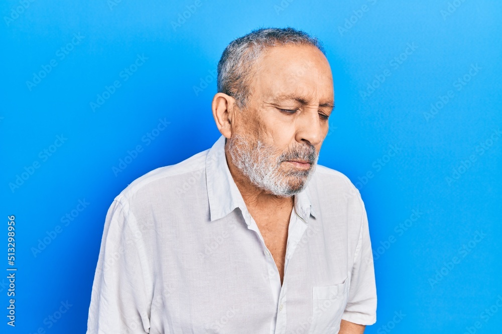 Handsome senior man with beard wearing casual white shirt with hand on stomach because indigestion, painful illness feeling unwell. ache concept. Handsome senior man with beard wearing casual white shirt with hand on stomach because indigestion, painful illness feeling unwell. ache concept.
