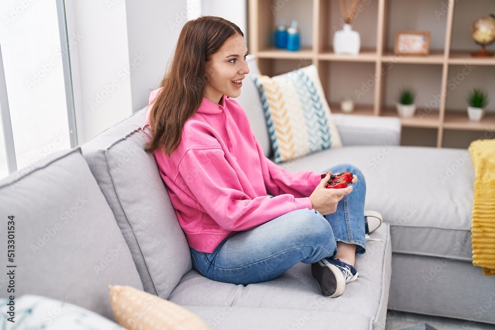 Young woman playing video game sitting on sofa at home Young woman playing video game sitting on sofa at home