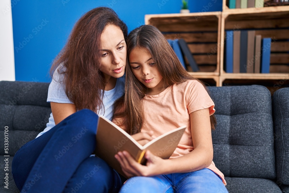 Obraz premium Woman and girl mother and daughter reading book at home