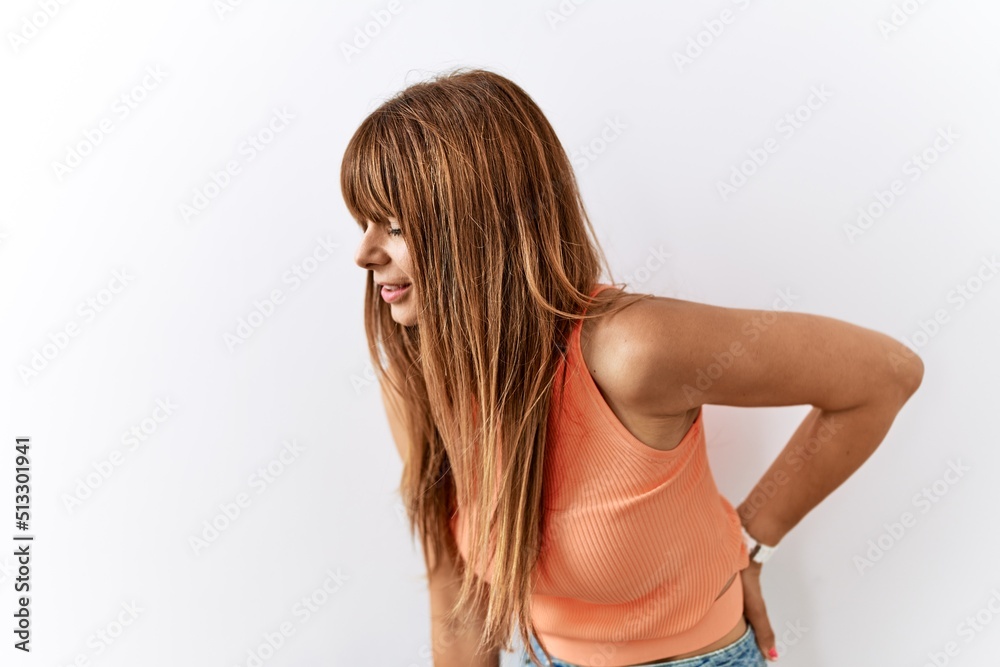 Hispanic woman with bang hairstyle standing over isolated background suffering of backache, touching back with hand, muscular pain Hispanic woman with bang hairstyle standing over isolated background suffering of backache, touching back with hand, muscular pain