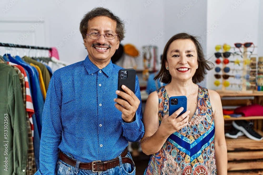 Middle age interracial couple at retail shop using smartphone with a happy and cool smile on face. lucky person. Middle age interracial couple at retail shop using smartphone with a happy and cool smile on face. lucky person.
