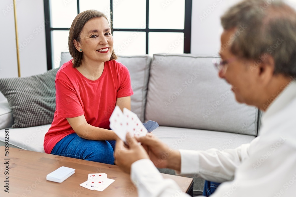Middle age man and woman couple smiling confident playing poker cards at home Middle age man and woman couple smiling confident playing poker cards at home