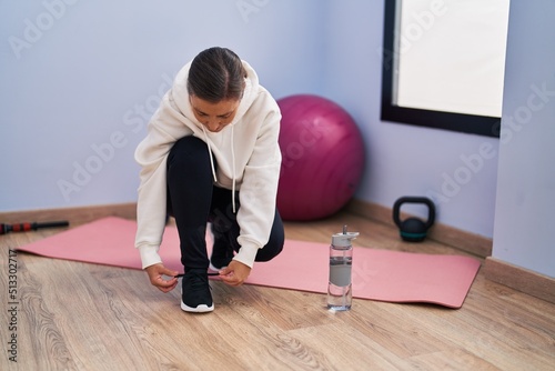 Middle age woman smiling confident tying shoe at sport center © Krakenimages.com