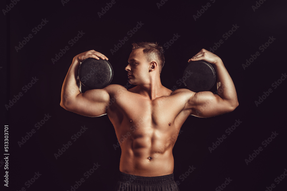 Power, strength, excellent body, bodybuilding, sports concept. Young handsome muscular fit man demonstrating perfect body and hold circles of cheese in black wax