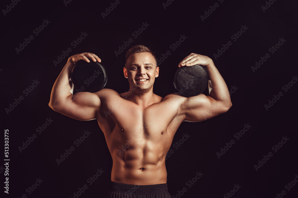 Power, strength, excellent body, bodybuilding, sports concept. Young handsome muscular fit man demonstrating perfect body and hold circles of cheese in black wax