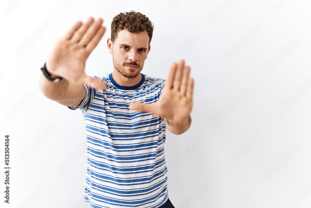 Handsome young man standing over isolated background doing frame using hands palms and fingers, camera perspective Handsome young man standing over isolated background doing frame using hands palms and fingers, camera perspective