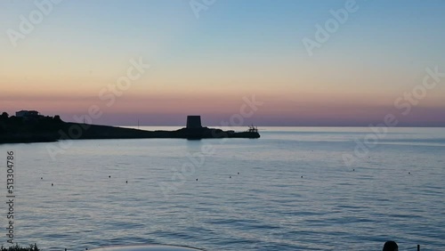 tramonto sul mare con un'antica torre e un'antico trabuco photo